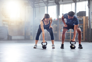 pareja fitness haciendo ejercicio pesas rusas o entrenamiento calentamiento gimansio hombres mujeres deportistas